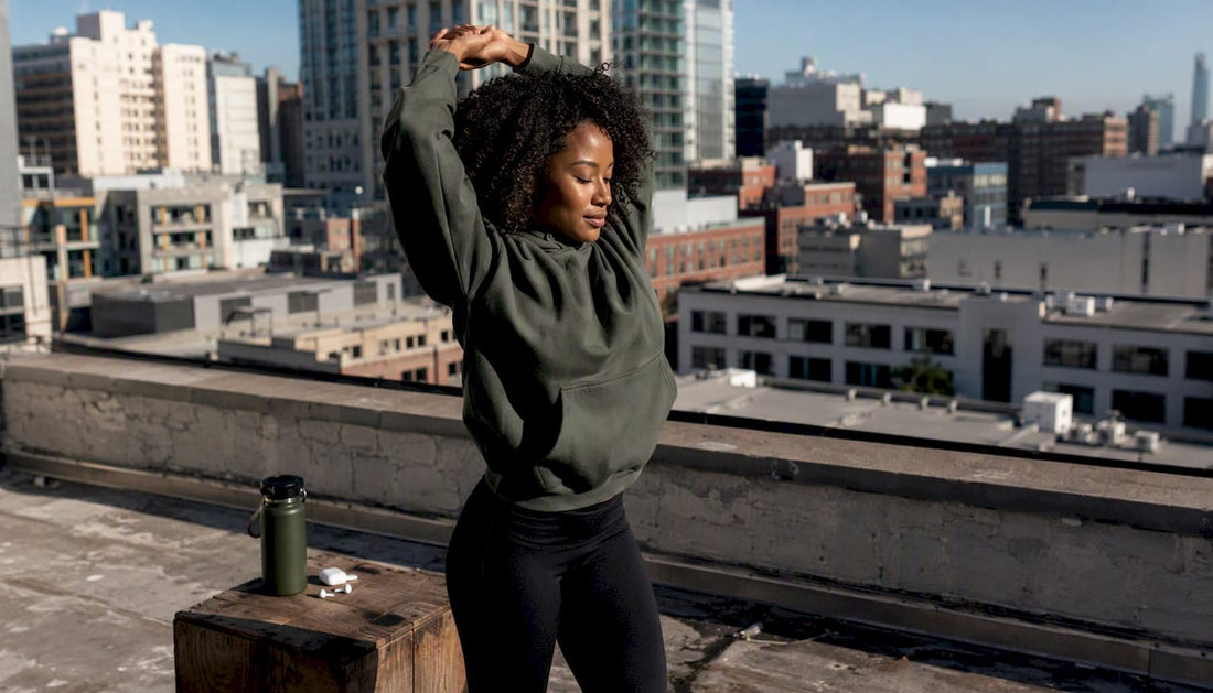 Athlete stretching on urban rooftop in hoodie