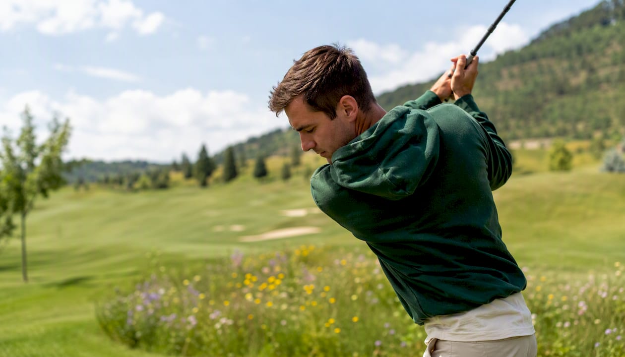 Golfer mid-swing in bold jewel-toned hoodie