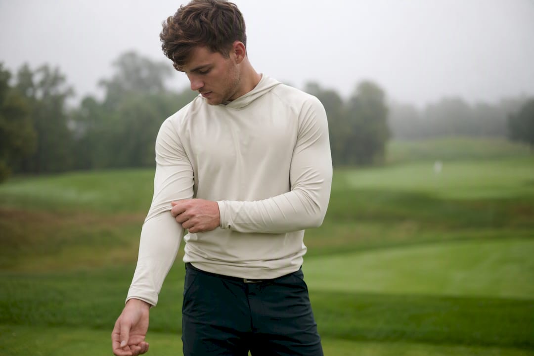 Golfer adjusting golf hoodie sleeve outdoors