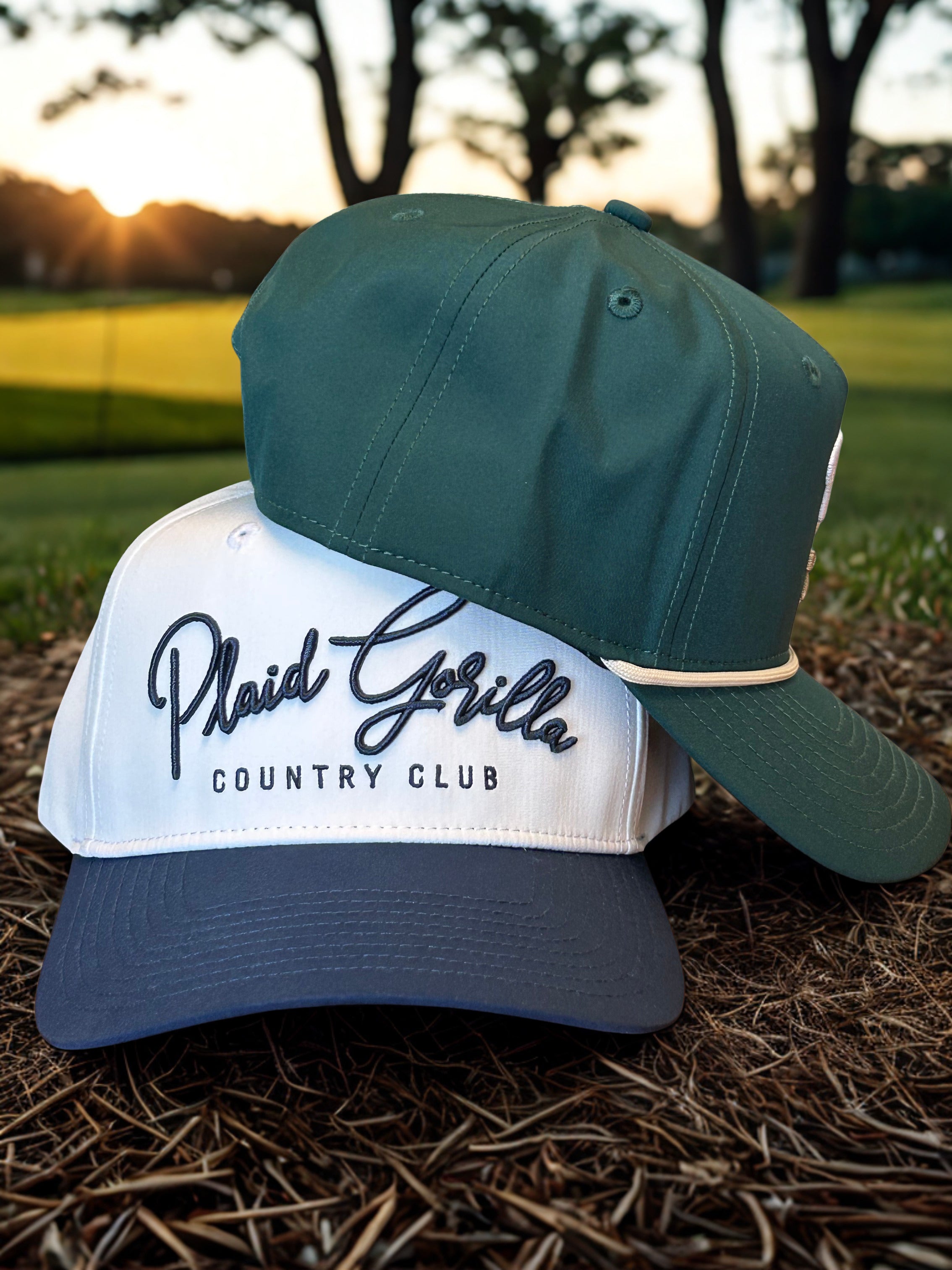 Plaid Gorilla Golf Country Club white and dark green golf hats stacked on a golf course at golden hour
