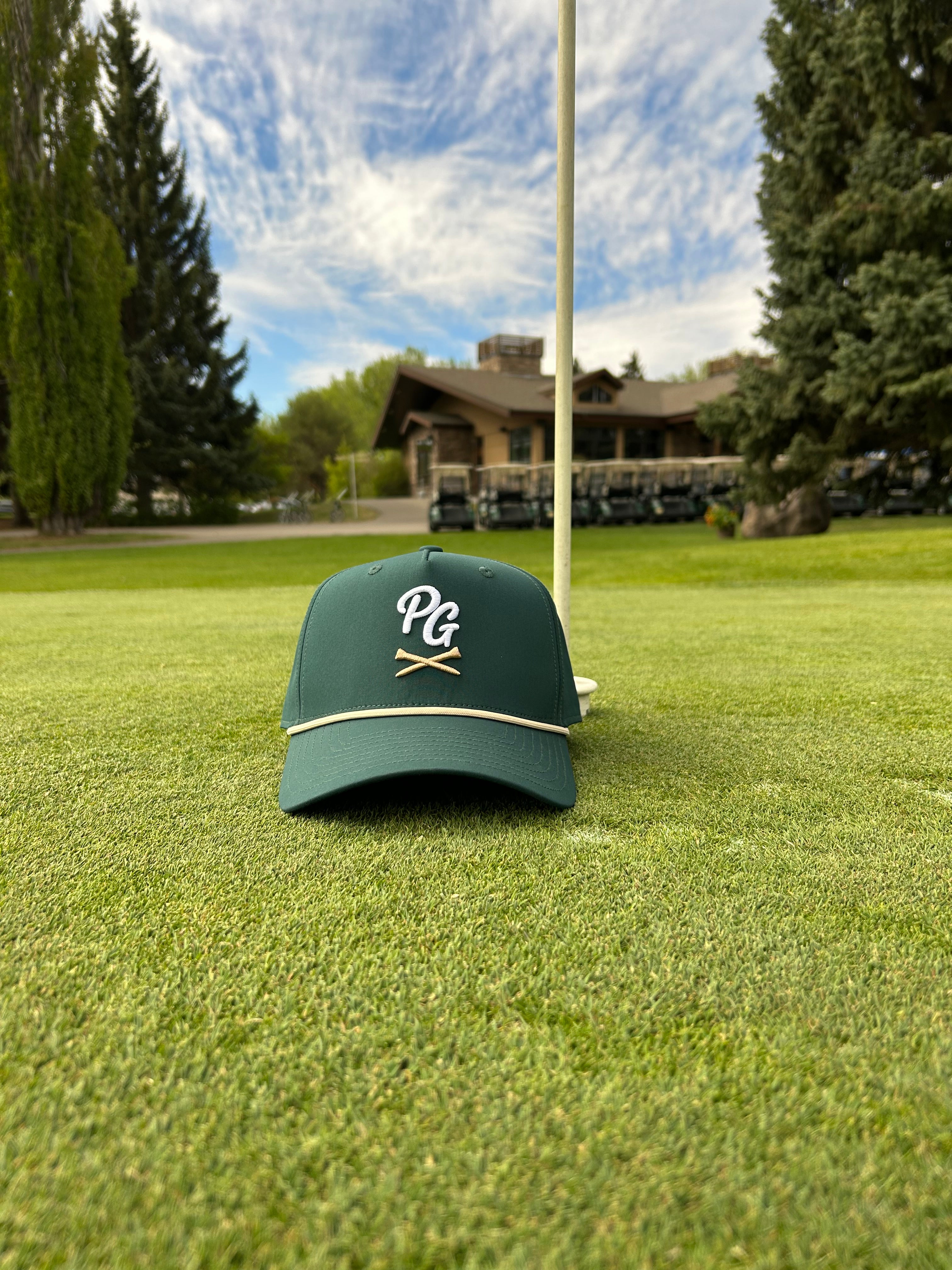 Plaid Gorilla Golf dark green rope hat with PG embroidered logo on a golf course putting green